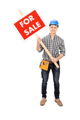 Young male engineer holding a for sale sign