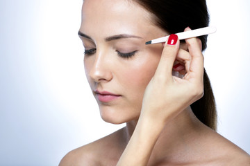 Closeup portrait of a cute young woman plucking eyebrows