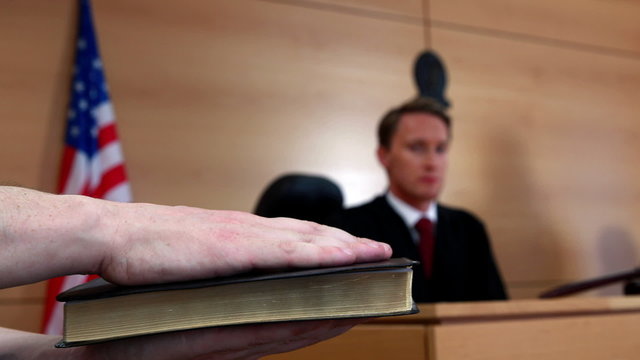 Judge looking at the witness swearing on bible