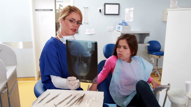 Pediatric dentist showing x-ray to little girl