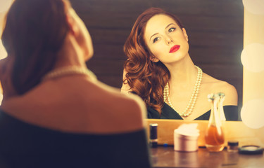 Portrait of a beautiful woman as applying makeup near a mirror