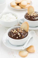 chocolate mousse with biscuits and nuts in white cups, vertical