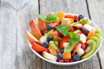 Fruit and berry salad in a bowl on a wooden background, close-up