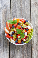 Fruit and berry salad on wooden table, vertical top view