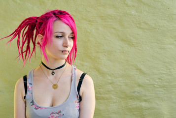 Woman with pink colored rasta hair in front of a green wall