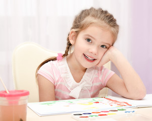 Cute smiling little girl drawing with paint and paintbrush