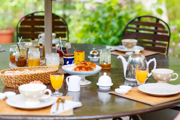 Table laid for breakfast outside with various jams coffee, crois