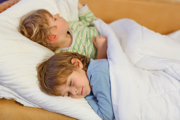 Obraz na płótnie Canvas Two little blond sibling boys sleeping in bed