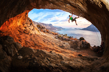 Young man lead climbing in cave before sunset - Powered by Adobe