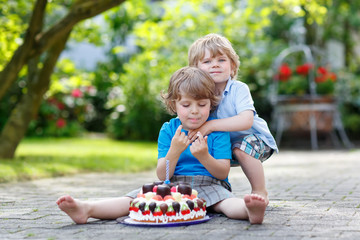 Two little children having fun together with big birthday cake