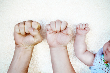 Young couple and their baby´s fists in one line.
