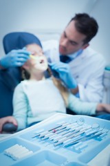 Male dentist examining girls teeth