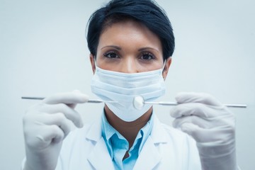 Female dentist in surgical mask holding dental tools