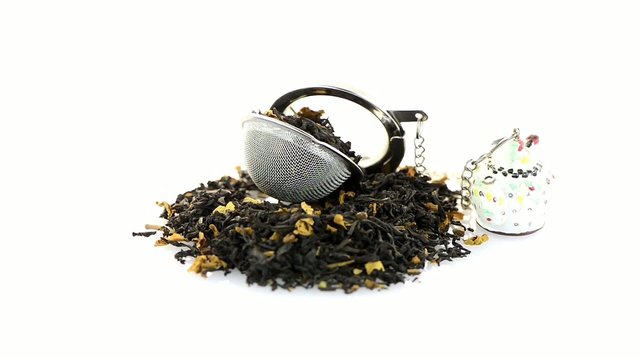 Aromatic black dry tea with petals and a tea strainer on white r