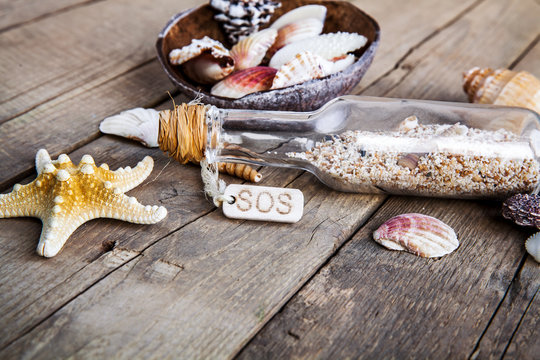 seashells frame on wooden background bottle with a message.
