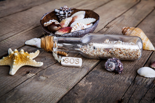 seashells frame on wooden background bottle with a message.