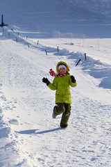 Девочка в зеленом бежит по снегу