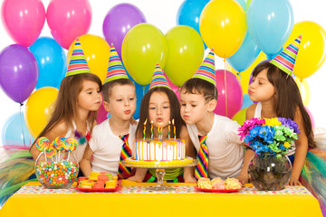 Kids celebrating birthday party and blowing candles on cake - Powered by Adobe