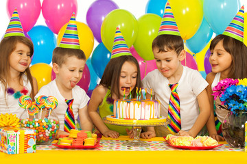 Group of joyful little kids with cake at birthday party