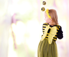 Rückansicht eines Kindes im Bienen Kleid - farbiger Hintergrund