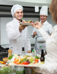 Female waiter taking dish at kitchen