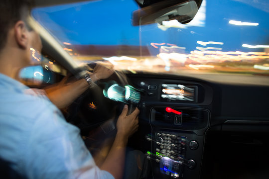 Driving a car at night - young man driving his modern car