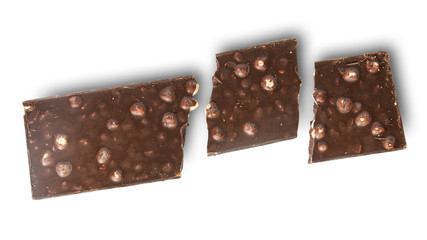 Broken tiles of dark chocolate with whole hazelnuts