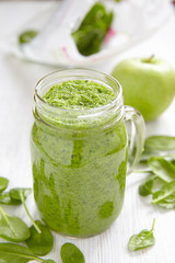 Apple and spinach smoothie in glass on a wooden background