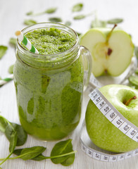 Apple and spinach smoothie in glass on a wooden background