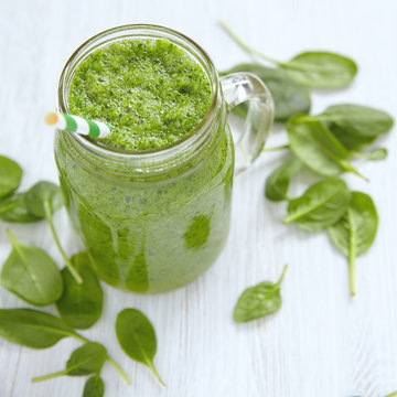 Apple and spinach smoothie in glass on a wooden background