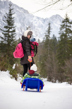 Mother pulling a child through snow on a toboggan