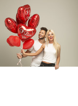Young smiling couple with red balloons heart