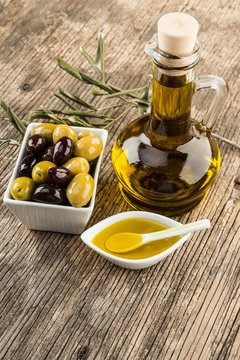 Fresh olives and olive oil on rustic wooden background