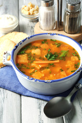 Carrot soup, cream and spoon, on  color wooden background