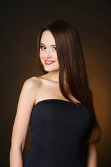 Fototapeta premium Beautiful young woman with long hair on dark brown background