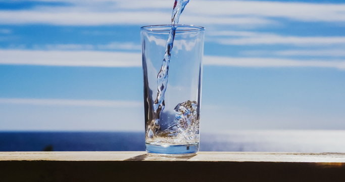 Blue water is flowing into the glass forming bubbles