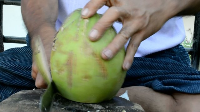 Thai native chef peeling the coconut preparing for coconut juice