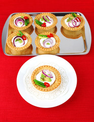 Tartlets with greens and vegetables with sauce on plate and