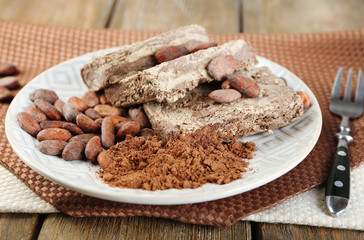 Sunflower halva with cocoa on plate, on wooden background