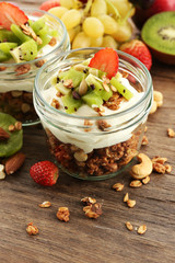 Healthy layered dessert with muesli and fruits on table
