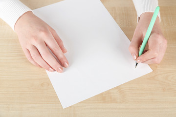 Obraz premium Female hand with pen and sheet of paper