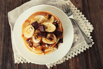 Stack of delicious pancakes with chocolate, honey, nuts and