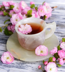 Beautiful fruit blossom with cup of tea on table close-up