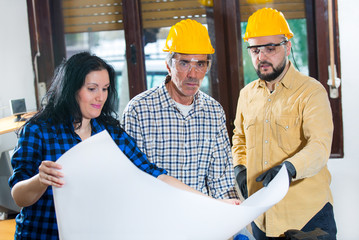 Construction worker and couple looking at the plan