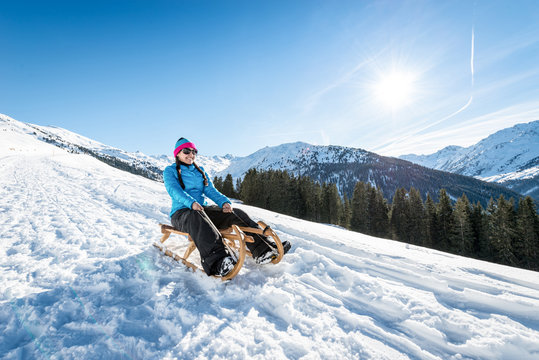 Girl sledging downhill in the snowy mountains