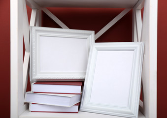 Photo frames with books on shelf, on color wall background