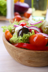 Greek salad in bow on wooden table background