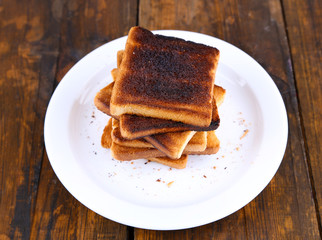 Burnt toast bread on plate, on wooden table background
