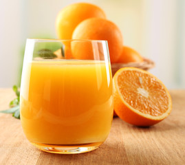Glass of orange juice and wicker basket with oranges
