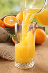 Pouring orange juice from glass carafe,